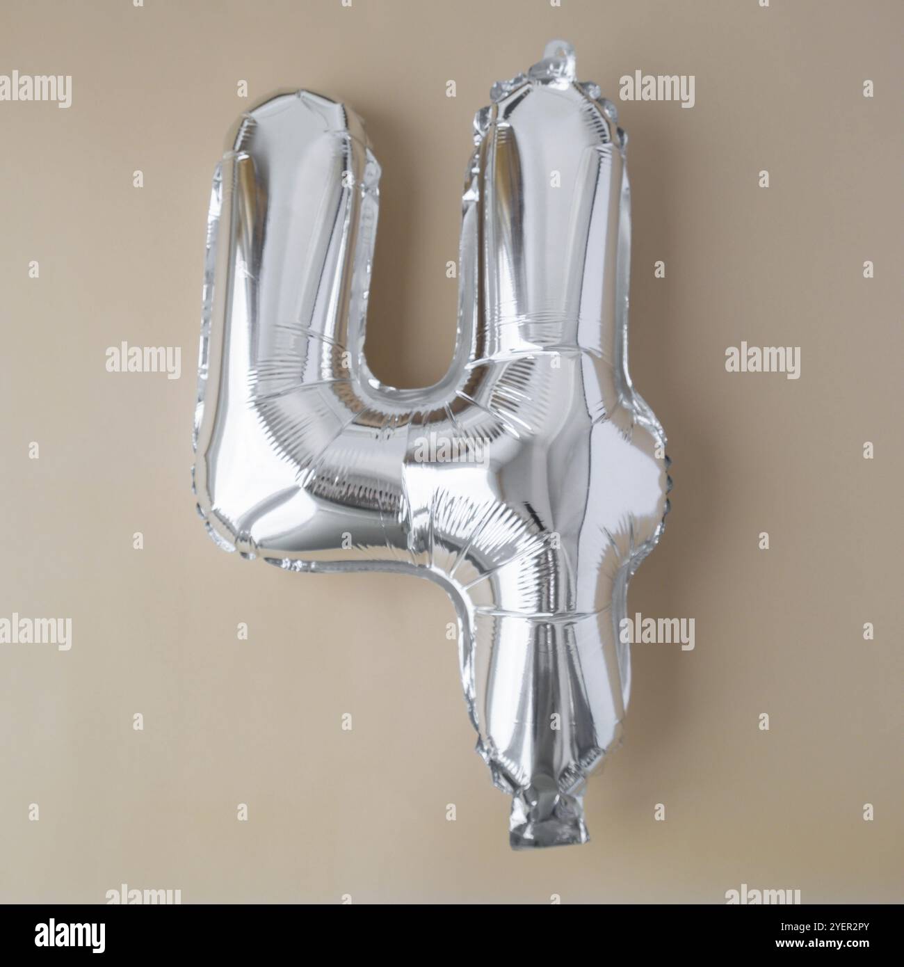 4 vier metallische Ballons auf beigefarbenem neutralen Hintergrund. Grußkarte Silberfolie Ballonnummer Happy Birthday Holiday Konzept. Kopierbereich für Text. Cel Stockfoto
