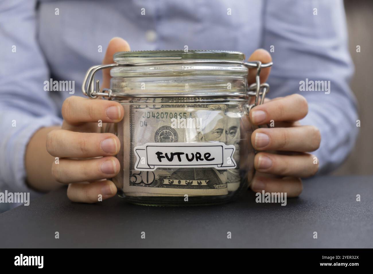 Unerkennbare Frau, die Spargeld in einem Glasgefäß hält, gefüllt mit Dollarscheine. ZUKÜNFTIGE Transkription vor dem Glas. Verwalten persönlicher Finanzen Stockfoto