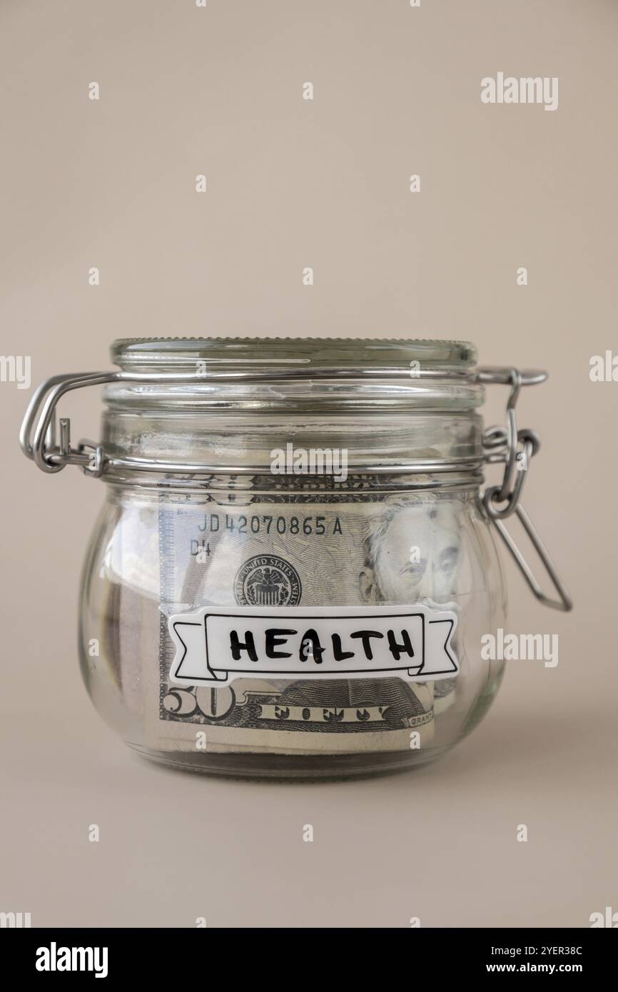 Sparen Sie Geld in einem Glasgefäß, gefüllt mit Dollarscheine. GESUNDHEITSTRANSKRIPTION vor dem Glas. Verwaltung persönlicher Finanzen zusätzliche Einnahmen für zukünftige Inse Stockfoto