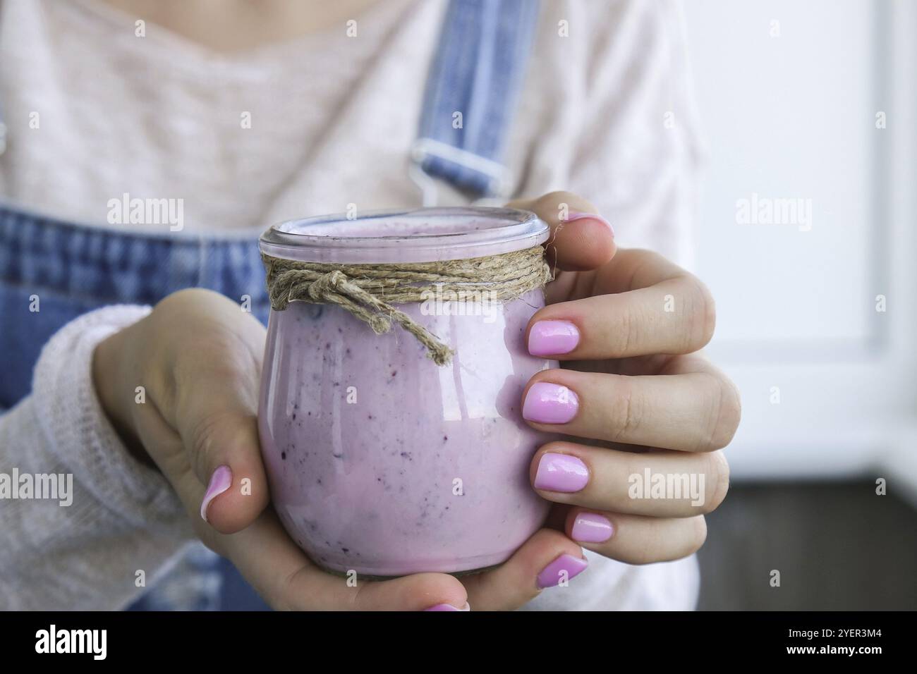 Weibliche Hände halten Blueberry Smoothie mit Heidelbeeren gekrönt. Frau, die ein Glas Frühstücksprotein-Smoothie-Getränk aus pürierten rohen Blauberri isst Stockfoto