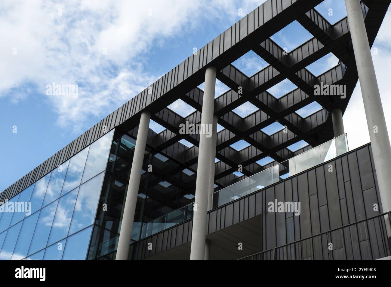 Modernes Bürogebäude mit Glasfassade auf klarem Himmel Hintergrund. Transparente Glaswand des Bürogebäudes mit Spiegelung von Wolken. Elemen Stockfoto