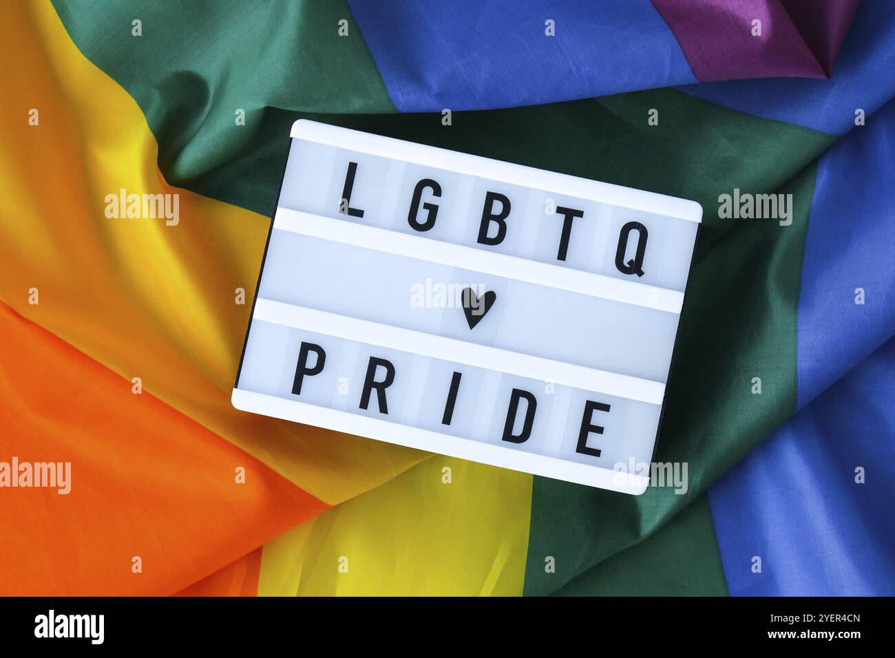 Regenbogenflagge mit Leuchtkasten und Text LGBTQ STOLZ. Regenbogen lgbtq Flagge aus Seidenmaterial. Symbol für den LGBTQ-stolz-Monat. Gleichberechtigung. Frieden und Freiheit Stockfoto