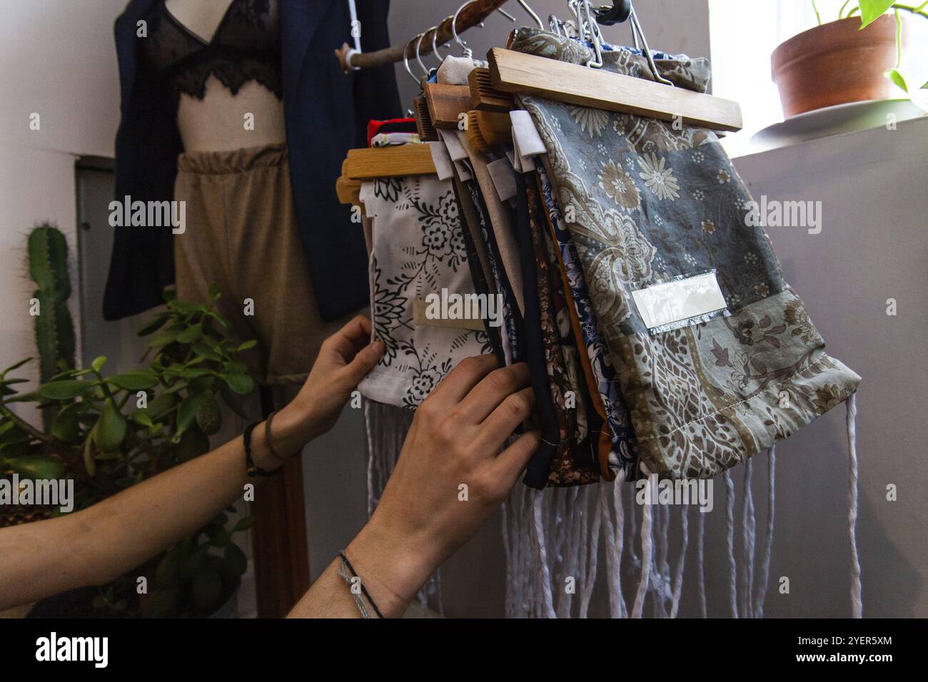 Eine junge Käufer sucht Kleine handgefertigte Taschen in einer Boutique zu speichern. Gemusterte wiederverwendbaren Taschen hängen von einem rustikalen Schiene in einer umweltfreundlichen Freund Stockfoto