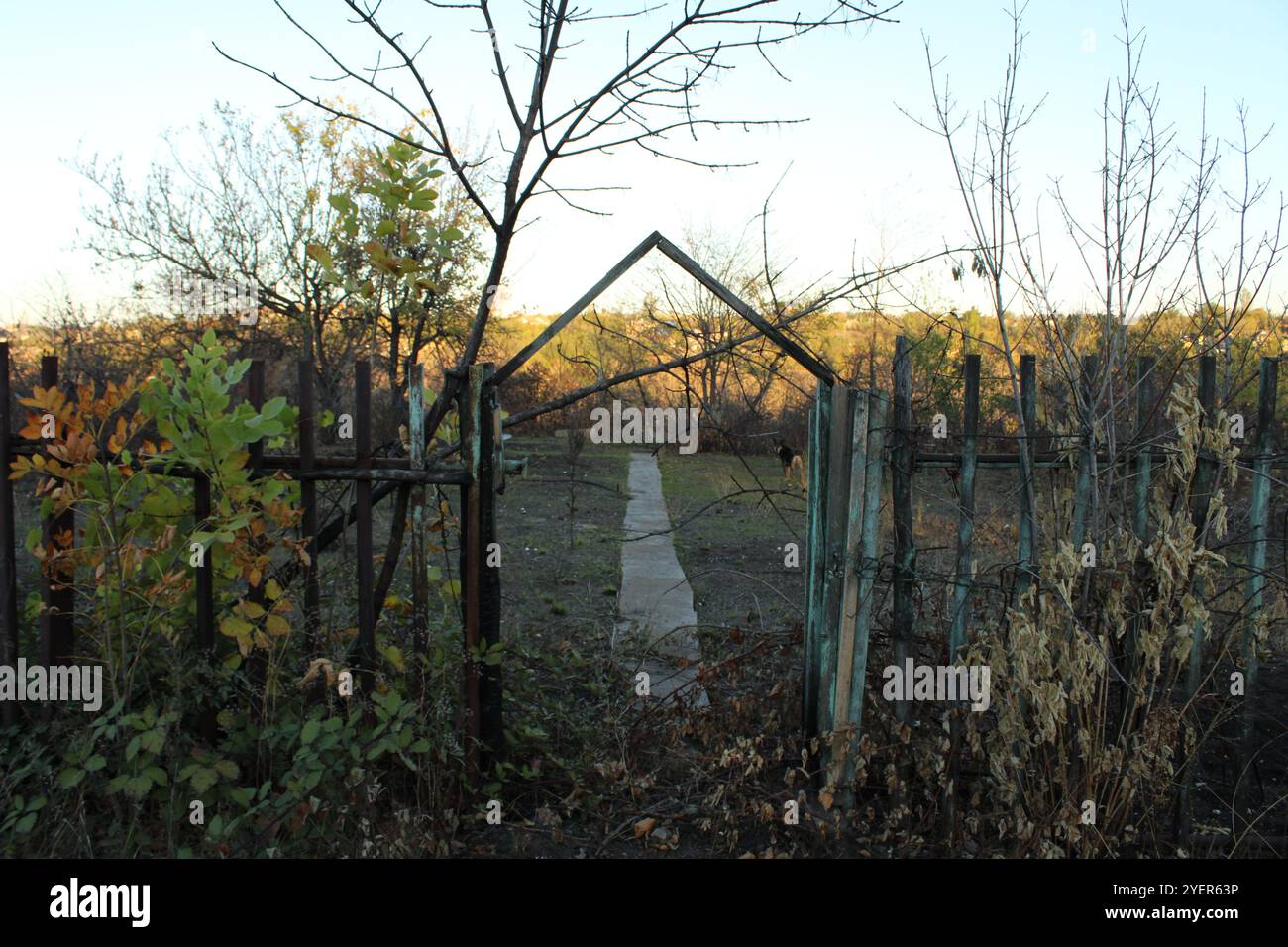 Ein alter Zaun mit Überresten eines Tores und einem Weg, der ins Unbekannte führt. Stockfoto