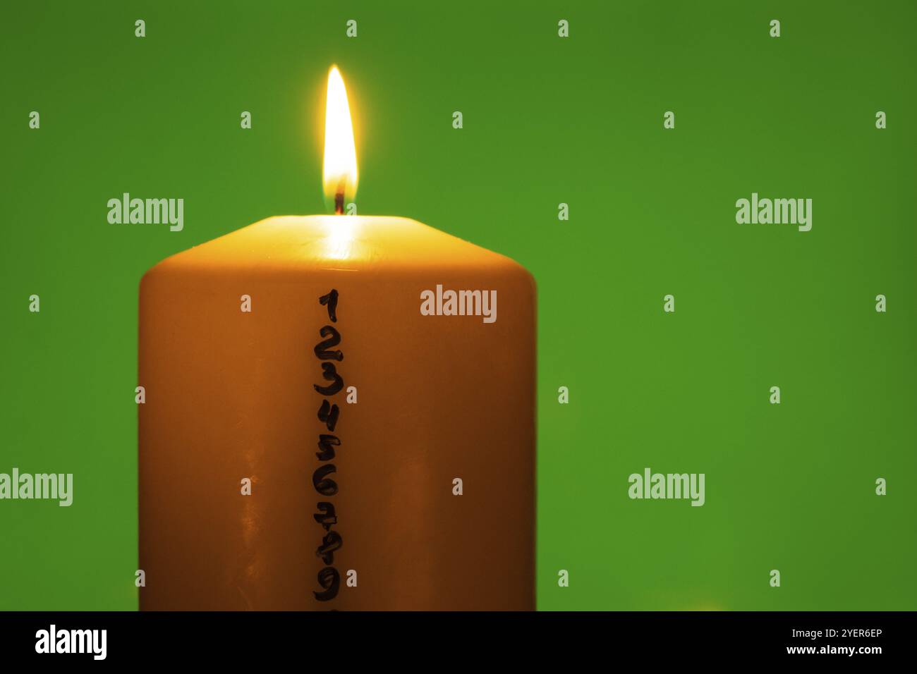 Kerze mit Adventskalender auf grünem Chroma-Schlüsselhintergrund traditionelle brennende Weihnachtswachskerzen mit Zahlen, die für Weihnachten herunterzählen. Schön Stockfoto