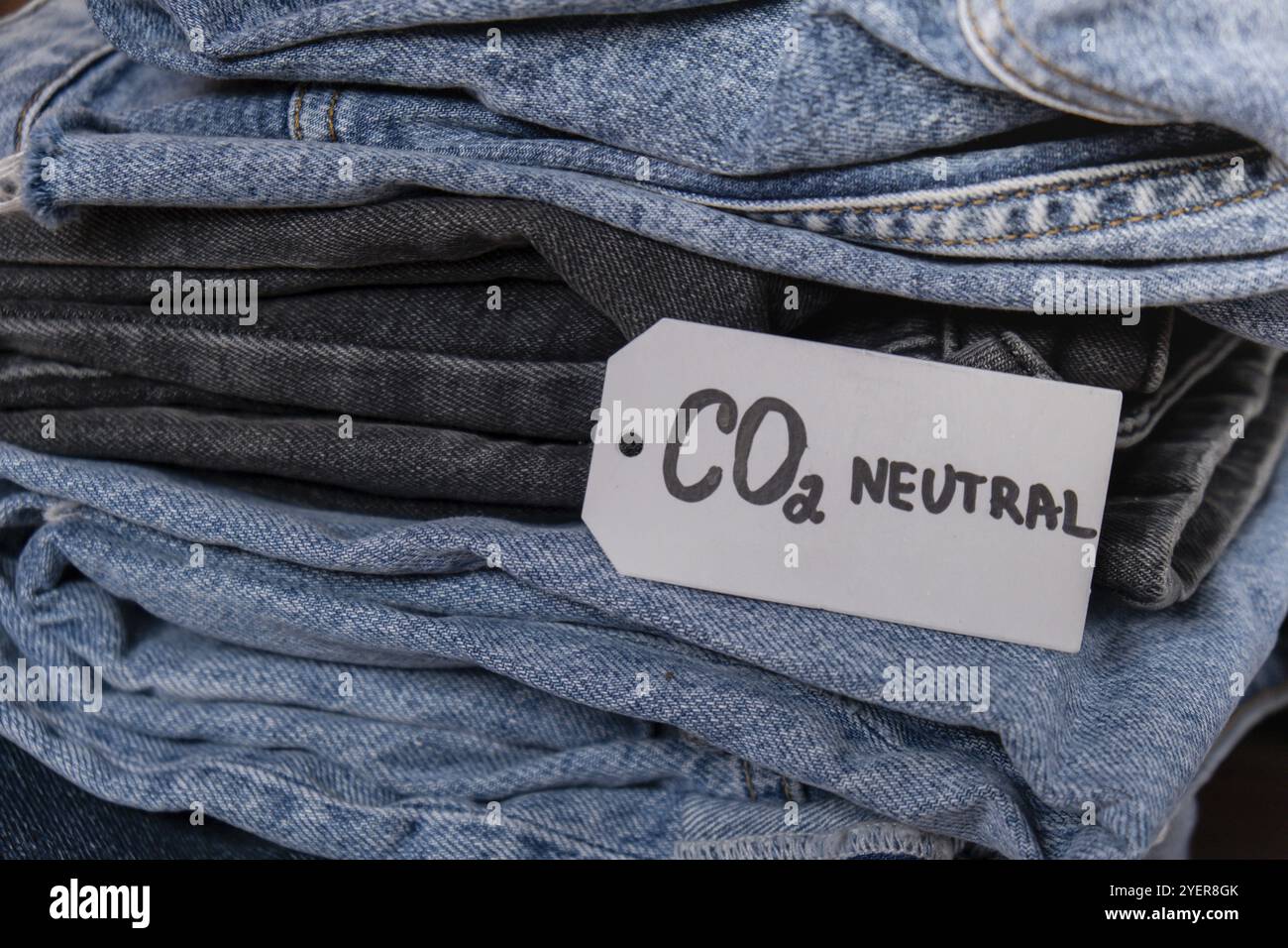 CO2-neutraler Emissions-Textnotiz auf dem Jeansstapel. Umweltfreundlich, Klimaschutz, umweltfreundlicher Kraftstoff und Schutzkonzept für die Erde. CO2-Emissionspapier Stockfoto