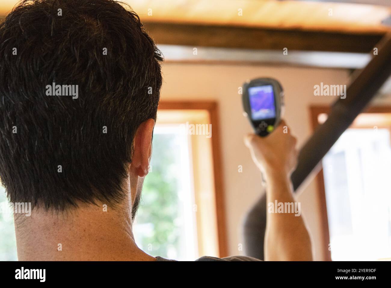 Eine extreme Nähe zu sehen, auf der Rückseite eines Mannes mit kurzen dunklen Haaren, mit einem Handheld IR-Bilder Kamera während einer Umweltqualität inspecti Stockfoto