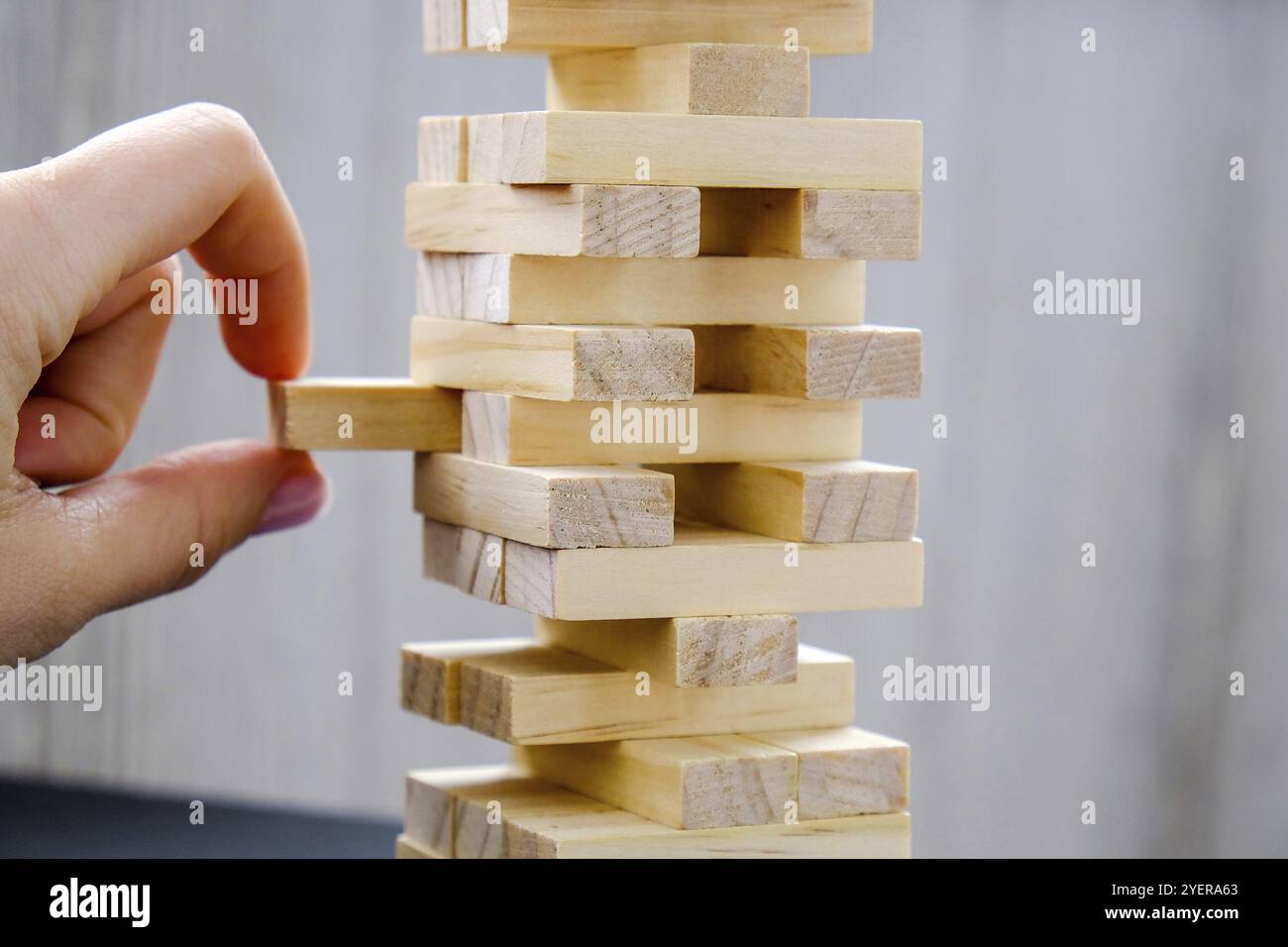 Gebäude aus Holzblöcken. Holz Blöcke Stack Spiel mit der Hand auf dem Hintergrund. Konzept der Teamarbeit. Blockturm mit Architekturmodell, Risiko von Mana Stockfoto