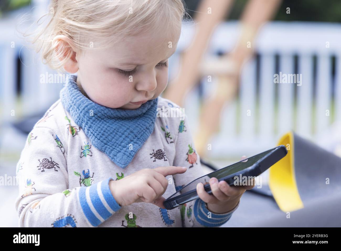 Nahaufnahme eines dreijährigen Jungen mit verwirrtem Gesichtsausdruck, der ein Smartphone hält und einen Touchscreen verwendet. Mit moderner Technologie und Kopierraum Stockfoto