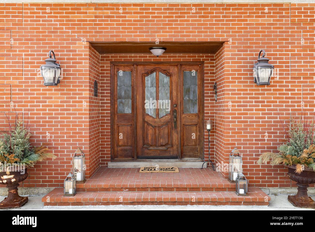 Eine Eingangstür in einem roten Backsteinhaus mit Stufen, die zu einer Holztür mit Milchglasfenstern führen. Stockfoto