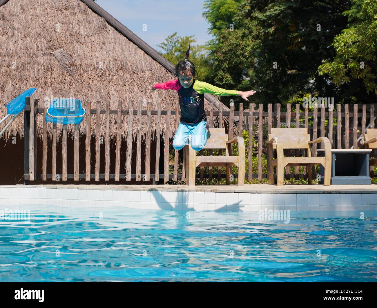 Mädchen, das Spaß hat, in den Pool zu springen. Sommerferien und Urlaubskonzept Stockfoto