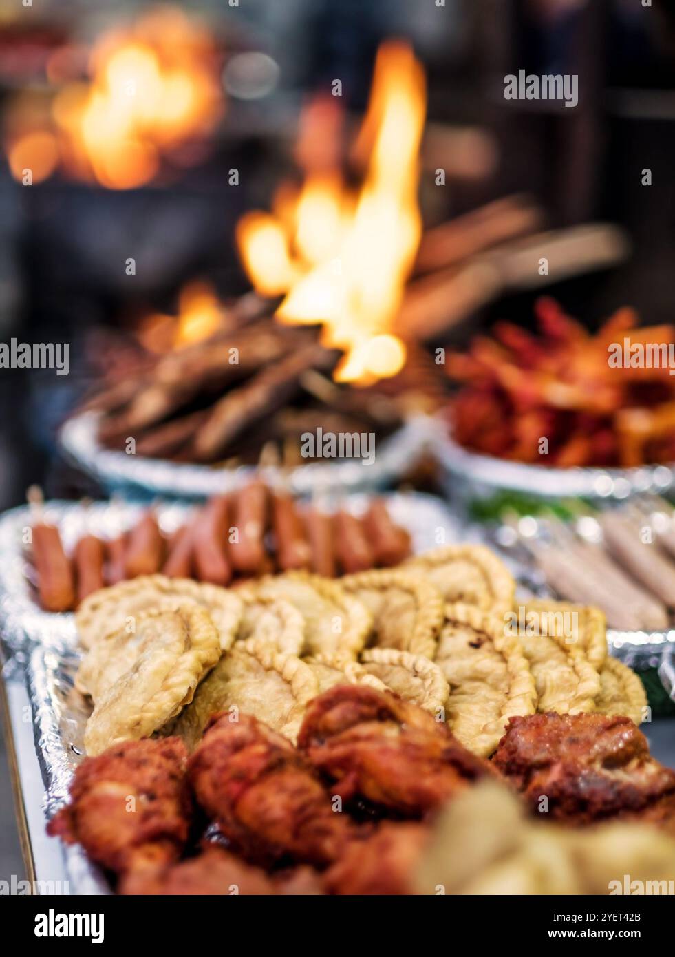 Frisch gebratener Fisch, Würstchen und frittierte Hähnchenfüße in der Nähe des Feuers auf dem nepalesischen Straßenmarkt Stockfoto