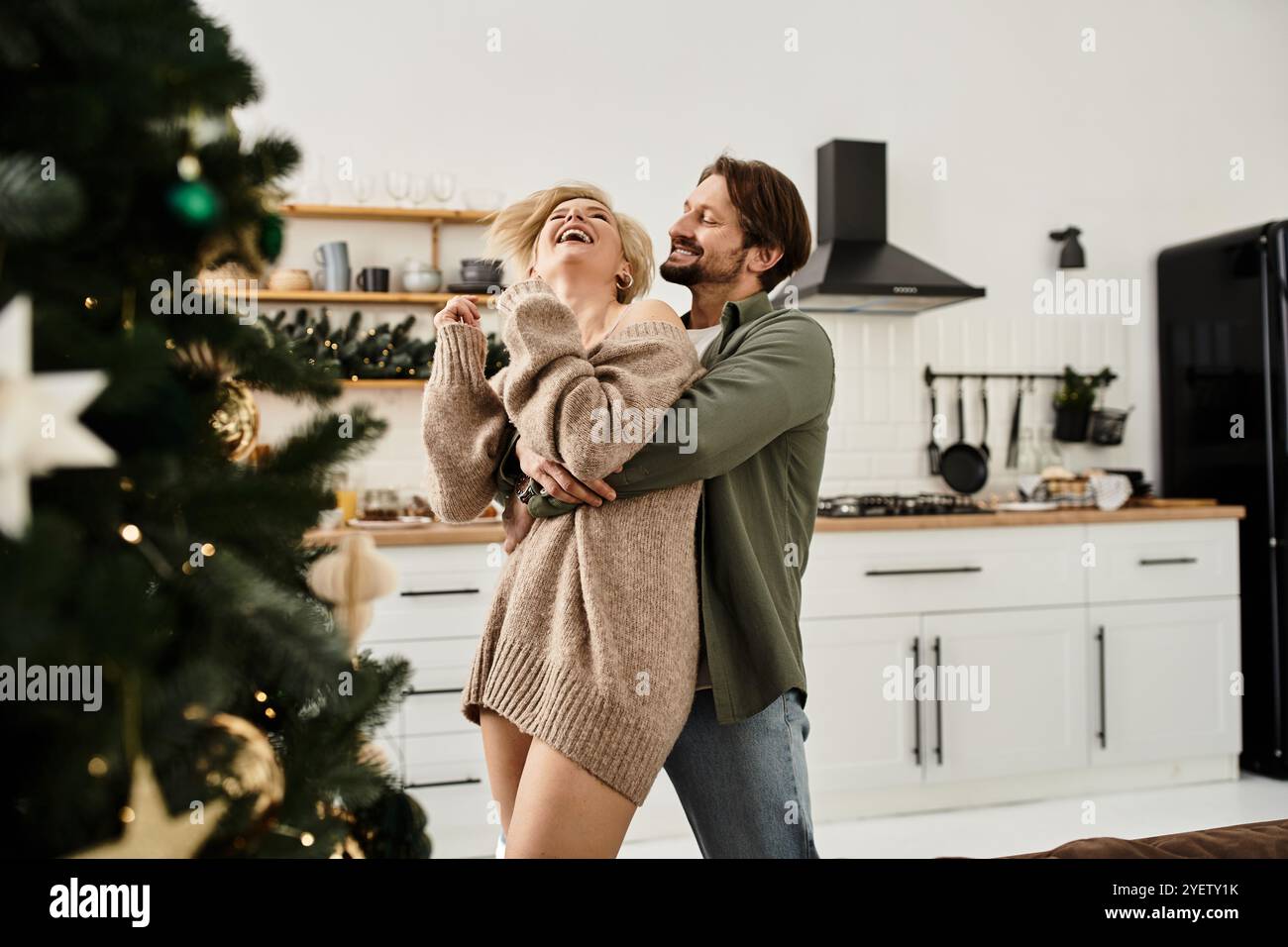 Ein Paar teilt Wärme und Lachen, während es sich in einer gemütlichen Urlaubsküche umgibt. Stockfoto