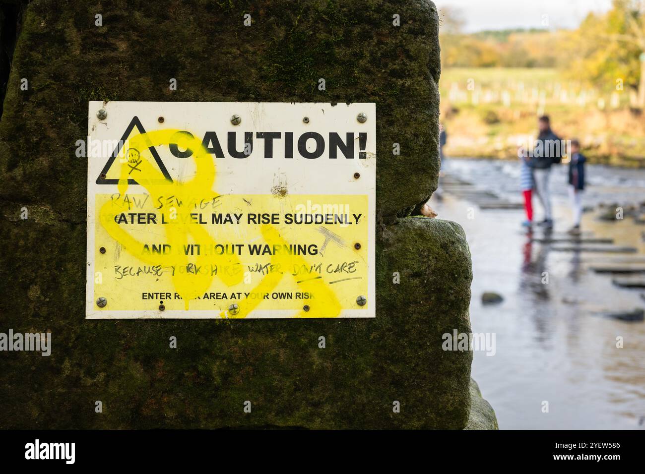 Graffiti auf dem Schild am River Wharfe: „Raw Sewage May rise Surprise and without warning because Yorkshire Water Don't Care“, Burley in Wharfedale, Ilkley Stockfoto