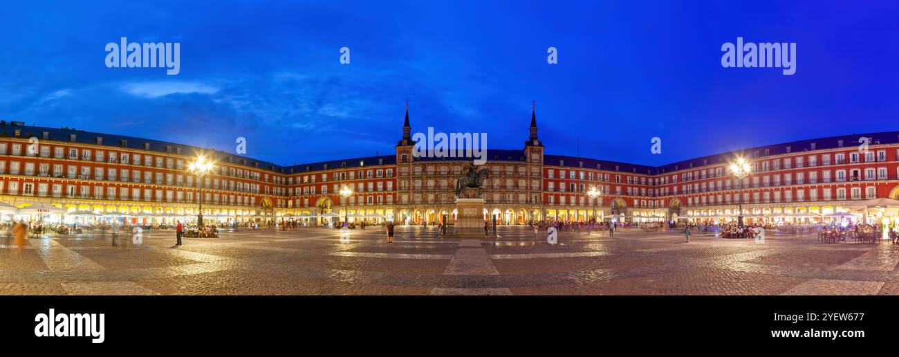 Panorama der belebten Plaza Mayor in Madrid, Spanien, beleuchtet in der Abenddämmerung mit ihrer berühmten Architektur, pulsierenden Lichtern und zahlreichen Besuchern. Stockfoto