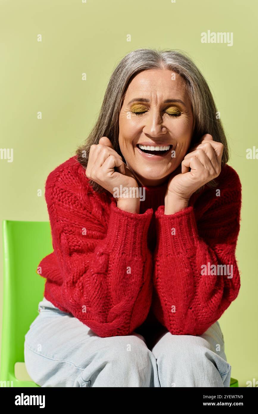 Eine fröhliche reife Frau mit grauem Haar genießt die Wintersaison und strahlt in ihrem roten Pullover Stil aus. Stockfoto