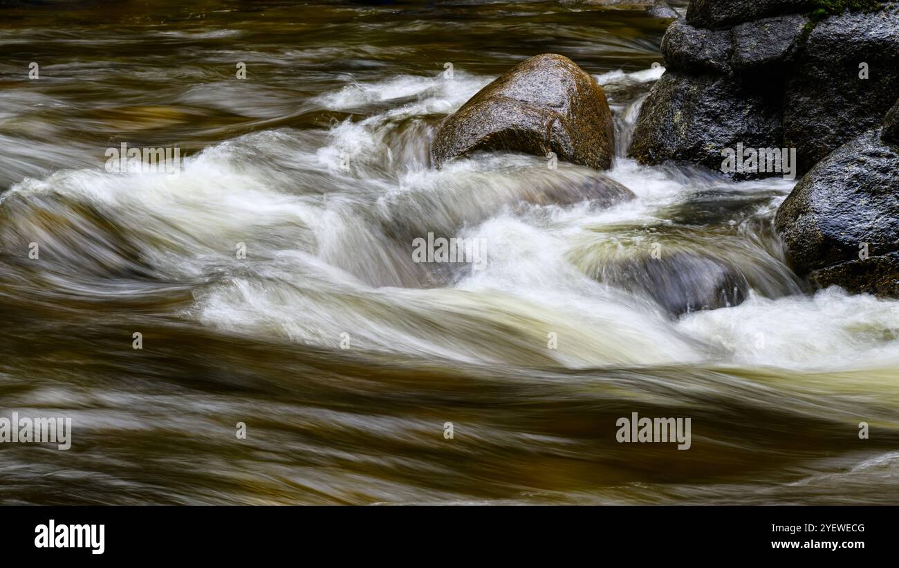 Dunkelbraunes Süßwasser mit weißen Highlights, vorbei an zerklüfteten Felsen Stockfoto