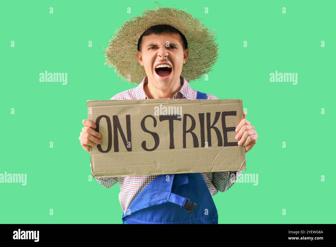 Protest gegen männlichen Landwirt, der ein Plakat mit STREIKTEXT vor grünem Hintergrund hält Stockfoto