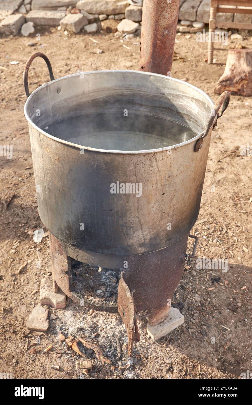 Topf Wasser, das auf das Feuer gelegt wird, um zu kochen, auf dem Hof im Land Stockfoto