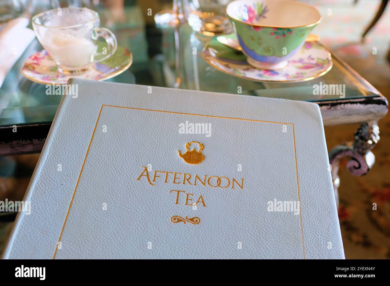 Hardcover-Menü mit weißem Afternoon Tea und Tisch im Hintergrund für traditionellen Tee und süße und herzhafte Leckereien am Nachmittag; goldene Buchstaben mit Prägung. Stockfoto