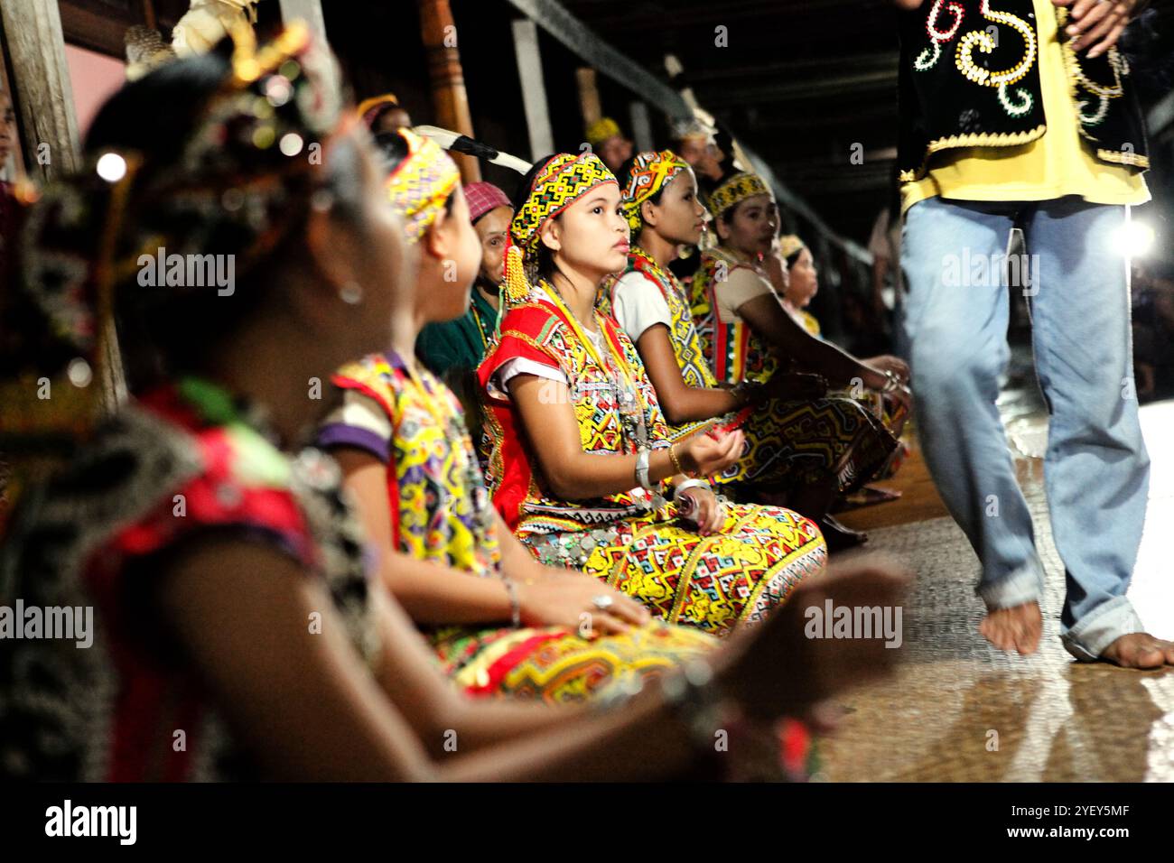 Junge Frauen in traditioneller Kleidung sitzen zu einer Begrüßungszeremonie während einer Ökotourismus-Veranstaltung im Bali Gundi Langhaus der traditionellen Dayak Taman Gemeinde in Sibau Hulu, Putussibau Utara, Kapuas Hulu, West Kalimantan, Indonesien. Laut Hernan Vales, Leiter der Abteilung für indigene Völker und Minderheiten der Vereinten Nationen, in einer Veröffentlichung des UN-Menschenrechtsbüros des Hohen Kommissars (OHCHR) im September 2024, sind Stimmen indigener Völker entscheidend für die Förderung ihrer Menschenrechte und ihrer Beteiligung an internationalen Entscheidungen. Stockfoto