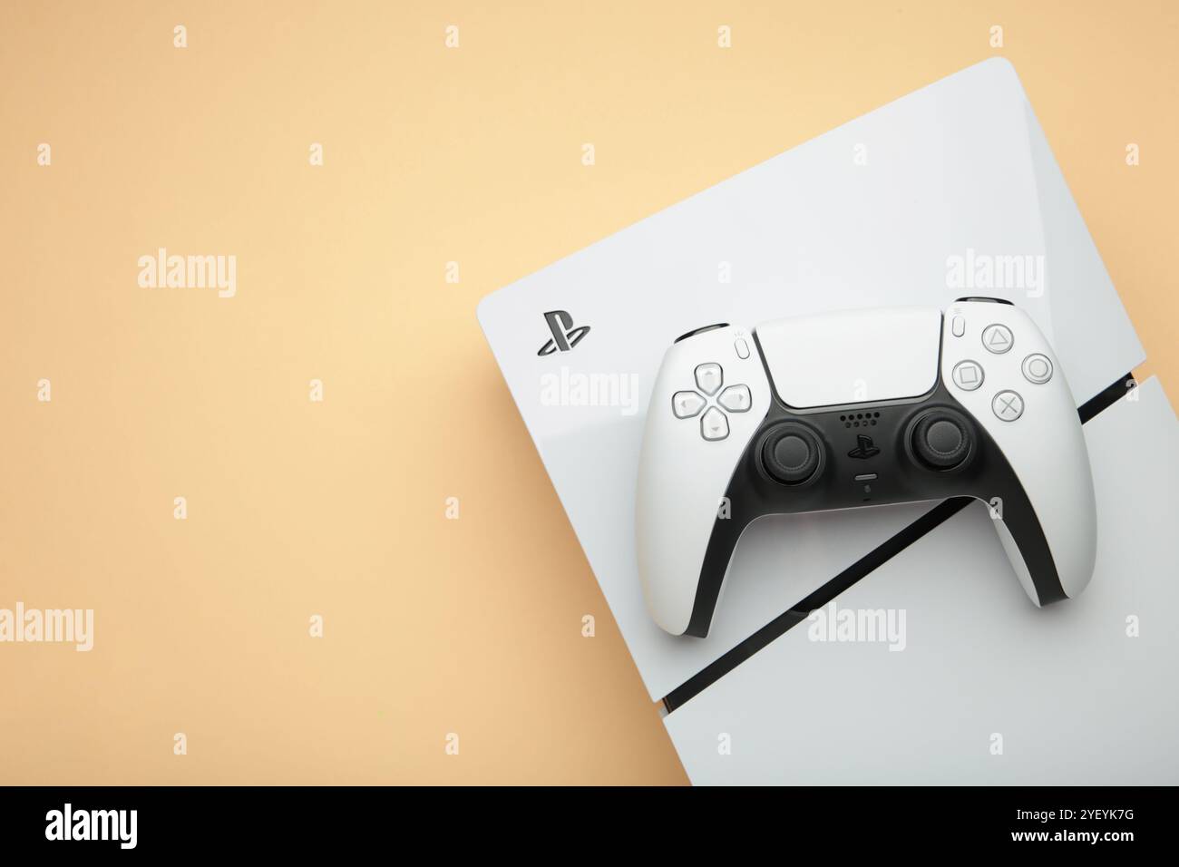 Mykolaiv, UKRAINE - Juli 2024: Weiße Konsole PlayStation 5 und Gamepad auf beigefarbenem Hintergrund Stockfoto