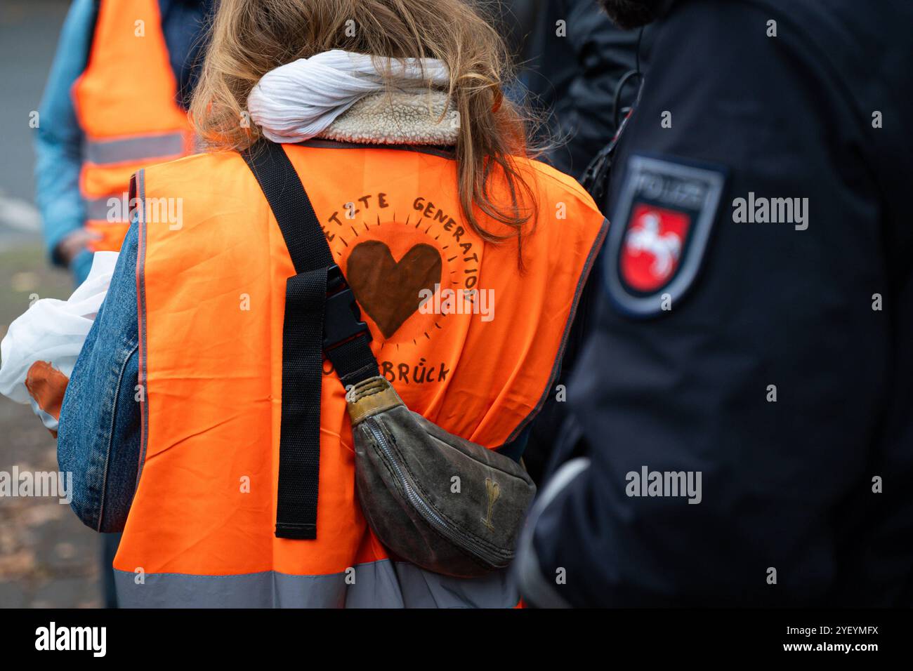 Landkreis Osnabrück, Deutschland 01. November 2024: Im Bild: Die Letzte Generation ist ein Zusammenschluss und seit Ende 2023 eingetragene Marke von Klimaaktivisten. Hier die letzte Generation bei einer Aktion in Osnabrück. Neben den Aktivisten steht ein Polizist. Niedersachsen *** Bezirk Osnabrück, Deutschland 01. November 2024 im Bild die letzte Generation ist seit Ende 2023 ein Verein und eingetragenes Warenzeichen von Klimaaktivisten hier die letzte Generation bei einer Aktion in Osnabrück Neben den Aktivisten steht ein Polizist Niedersachsen Copyright: XFotostandx/xKippx Stockfoto