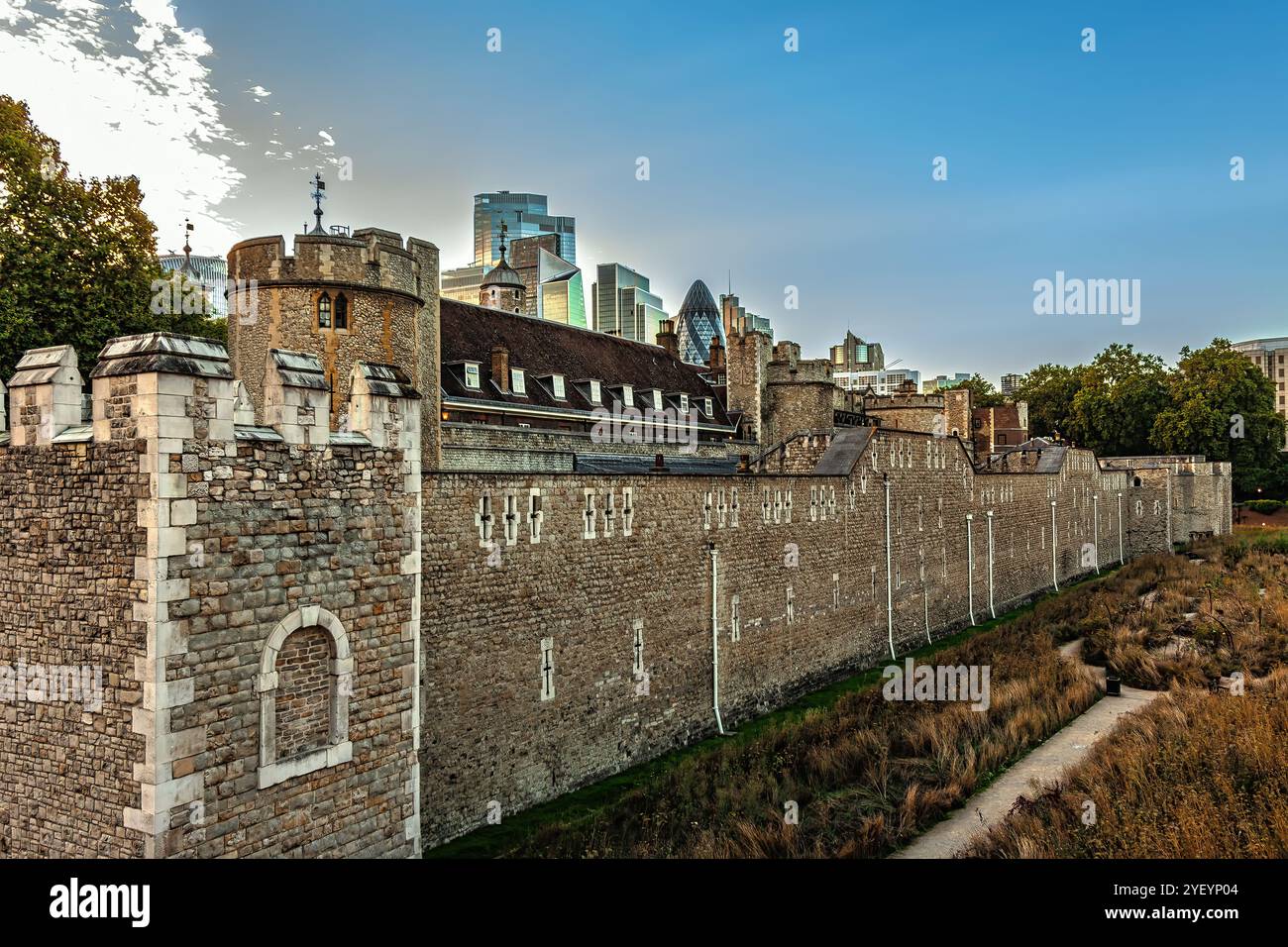 Die hohen Mauern des Tower of London, im Hintergrund die Wolkenkratzer der City of London mit der besonderen Form des Gherkin. England Stockfoto