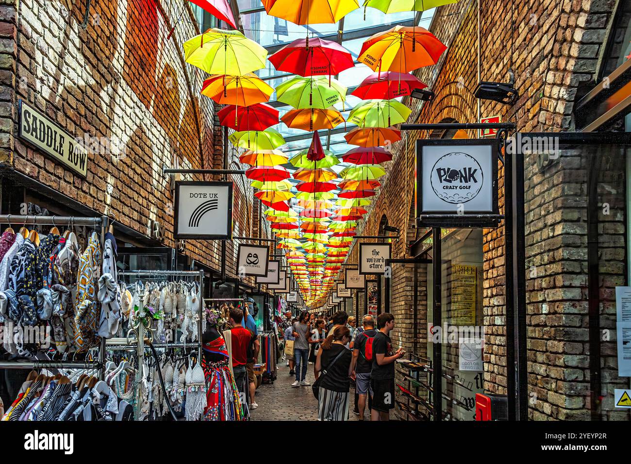 Leute, typische Geschäfte und bunte Regenschirme hängen auf dem Dach des Camden Town Market. London, England, Europa Stockfoto