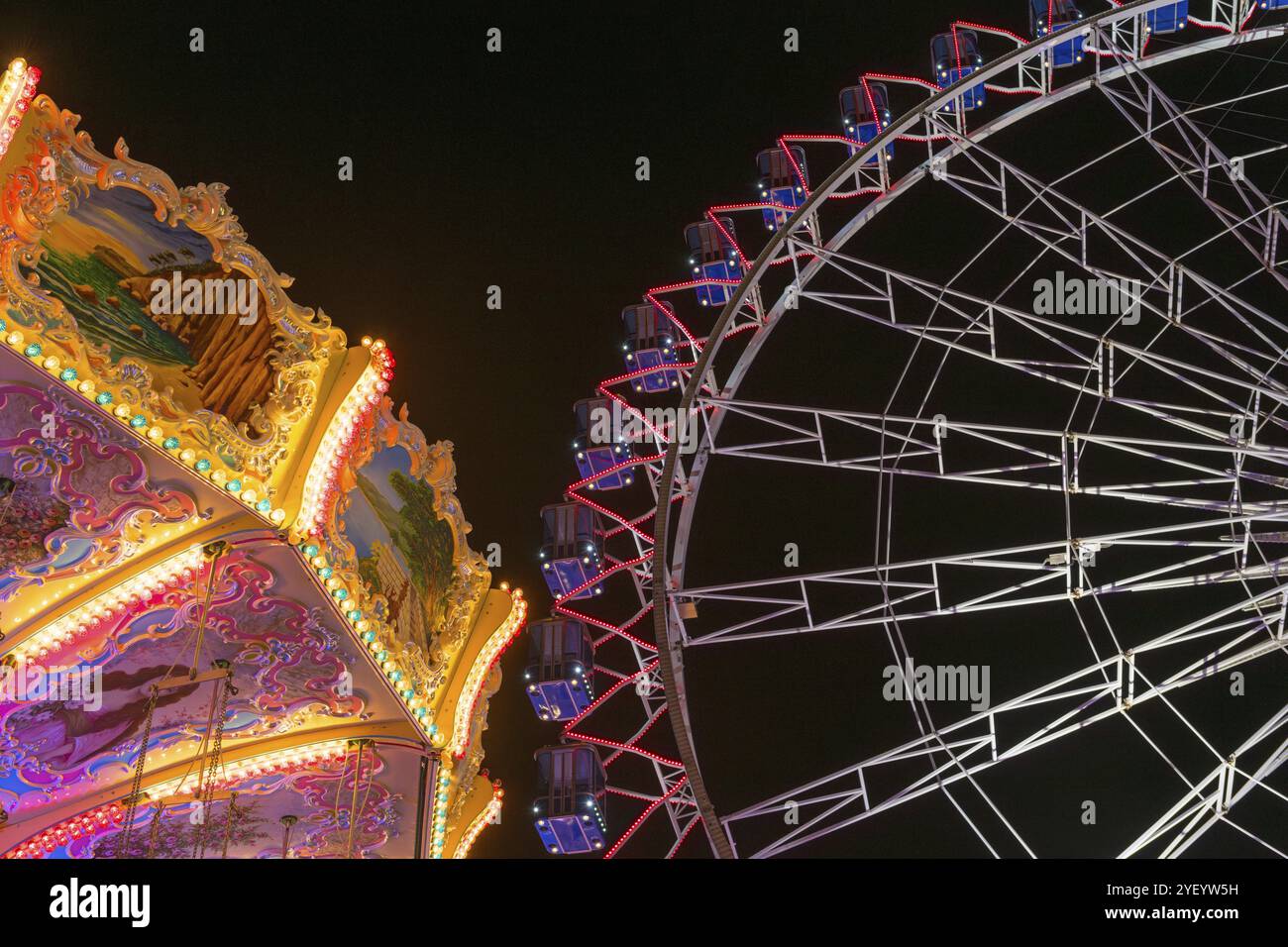 Ein Jahrmarkt bei Nacht mit beleuchtetem Kettenkarussell und Riesenrad, Europa Rad, Fahrten, Wellenflug, Cannstatter Wasen, Volksfest Bad Cannstatt, Stockfoto