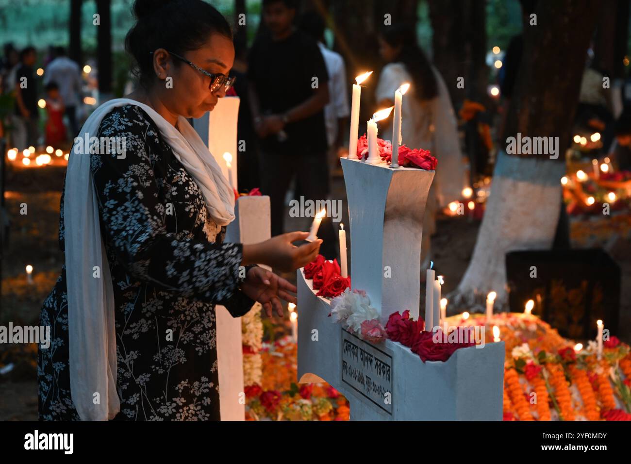 Christliche Gläubige zünden am 2. November 2024 auf einem Friedhof auf dem Wari Cemetery der Heilig-Kreuz-Kirche in Dhaka, Bangladesch, Kerzen an den Gräbern von Verwandten an Stockfoto