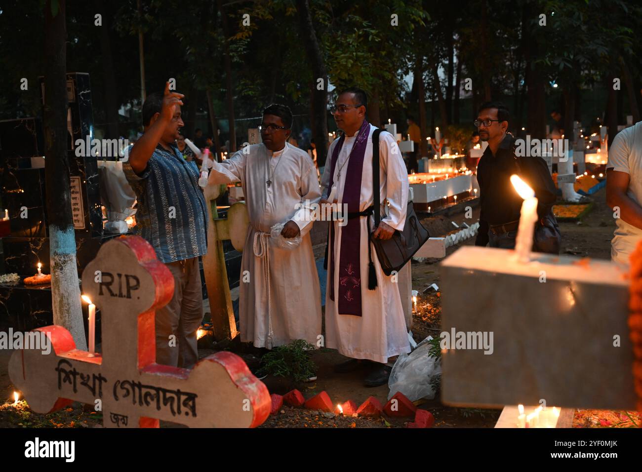 Christliche Gläubige zünden am 2. November 2024 auf einem Friedhof auf dem Wari Cemetery der Heilig-Kreuz-Kirche in Dhaka, Bangladesch, Kerzen an den Gräbern von Verwandten an Stockfoto