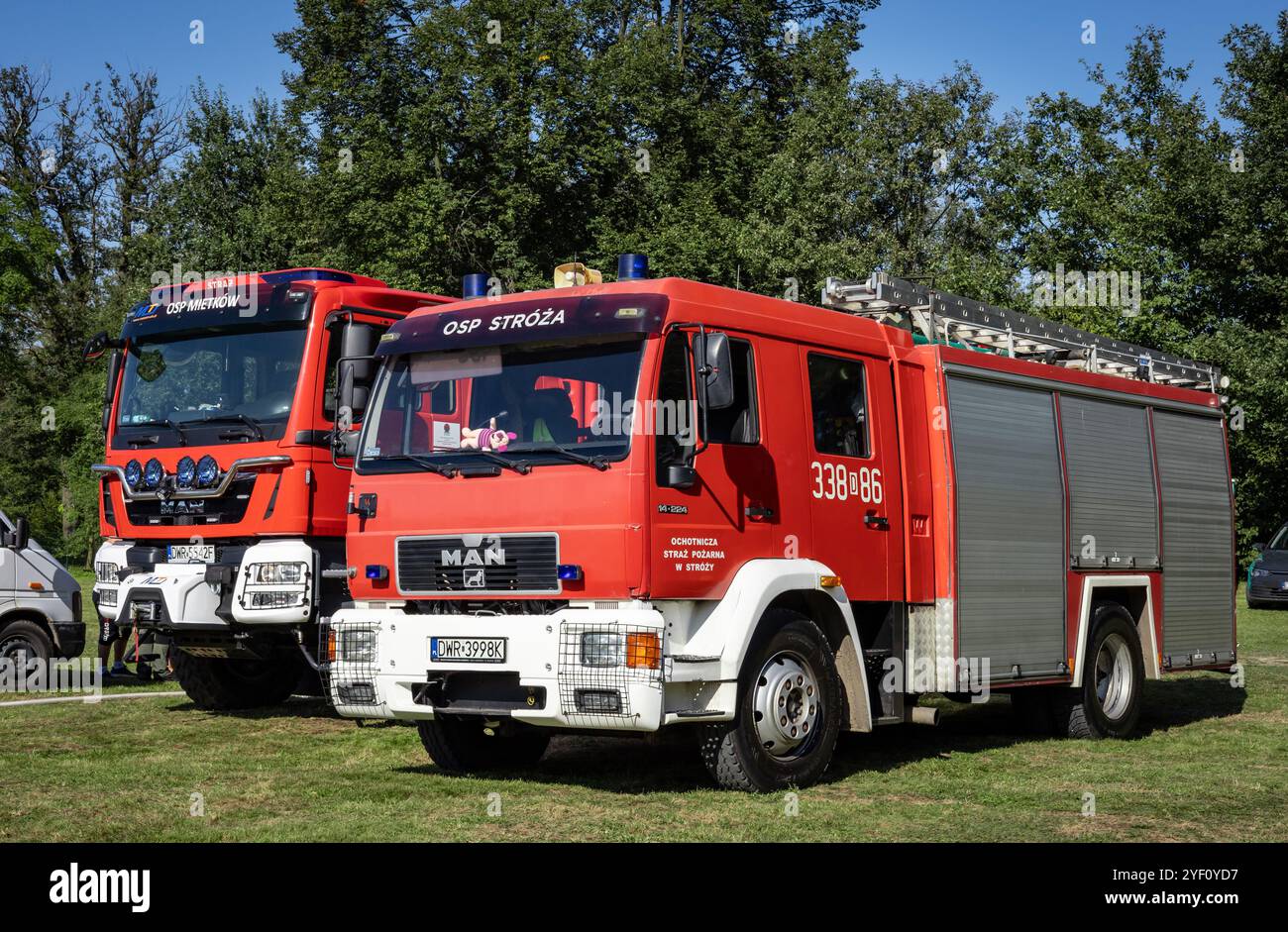 Domanice, Polen - 24. August 2024: Zwei rote Feuerwehrfahrzeuge parken draußen, keine Leute. Erntefest in Domanice, Mietkow, Woiwodschaft Niederschlesien. Stockfoto