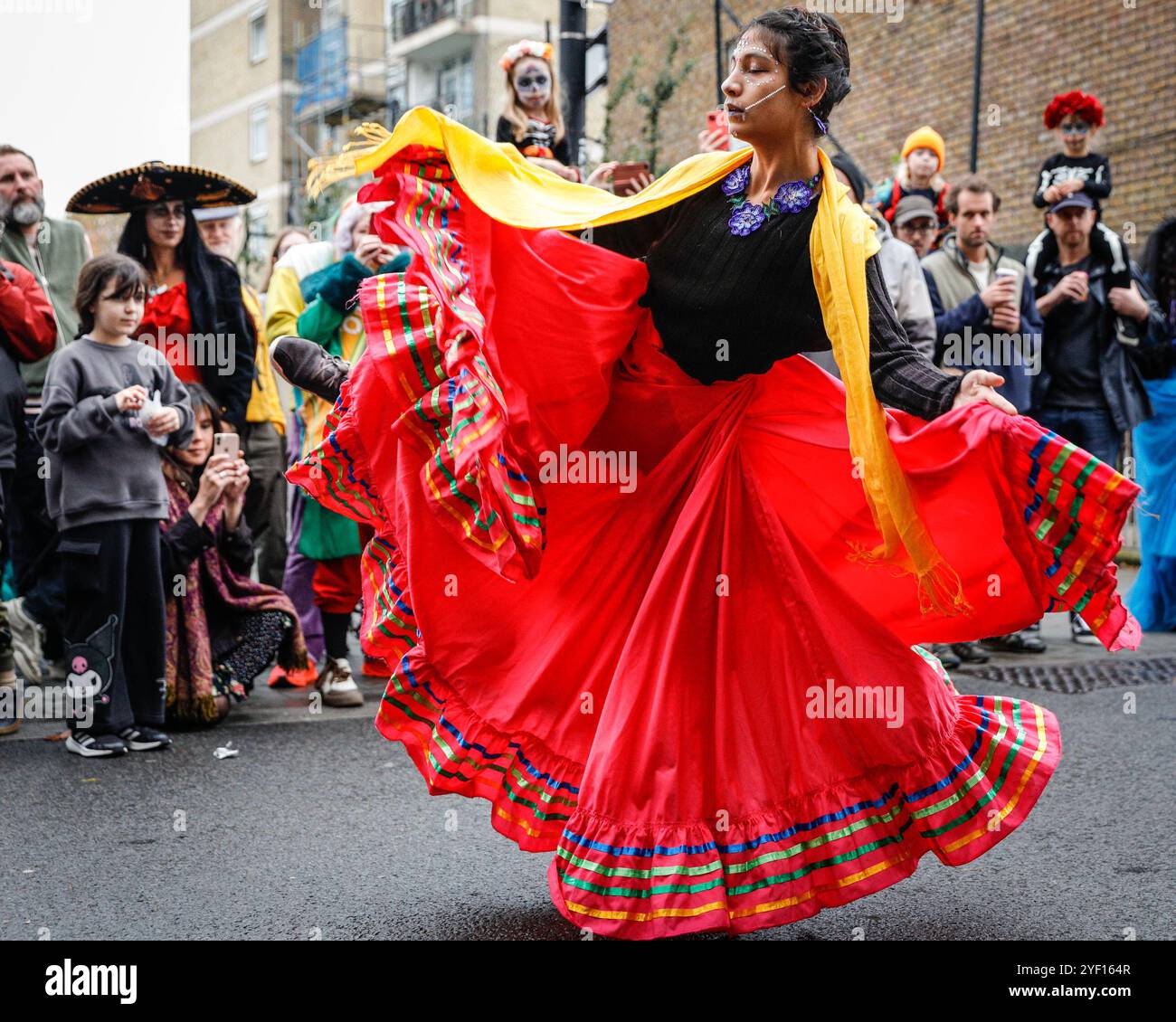 London, Großbritannien. November 2024. Eine Tänzerin unterhält die Massen. Die Teilnehmer, viele in lebendigen Gesichtsbemalungen und Kostümen, versammeln sich in der Columbia Road. Der jährliche Tag der Toten und die Parade auf und um die Columbia Road in grüßt den mexikanischen Tag der Toten, ein freudiger Anlass trotz seines Namens, der das Vergehen geliebter Menschen ehrt. Die Teilnehmer kommen in farbenfrohen Kostümen auf. Quelle: Imageplotter/Alamy Live News Stockfoto