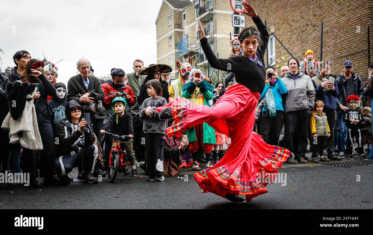 London, Großbritannien. November 2024. Eine Tänzerin unterhält die Menge. Die Teilnehmer, viele in lebendigen Gesichtsbemalungen und Kostümen, versammeln sich in der Columbia Road. Der jährliche Tag der Toten und die Parade auf und um die Columbia Road in grüßt den mexikanischen Tag der Toten, ein freudiger Anlass trotz seines Namens, der das Vergehen geliebter Menschen ehrt. Die Teilnehmer kommen in farbenfrohen Kostümen auf. Quelle: Imageplotter/Alamy Live News Stockfoto