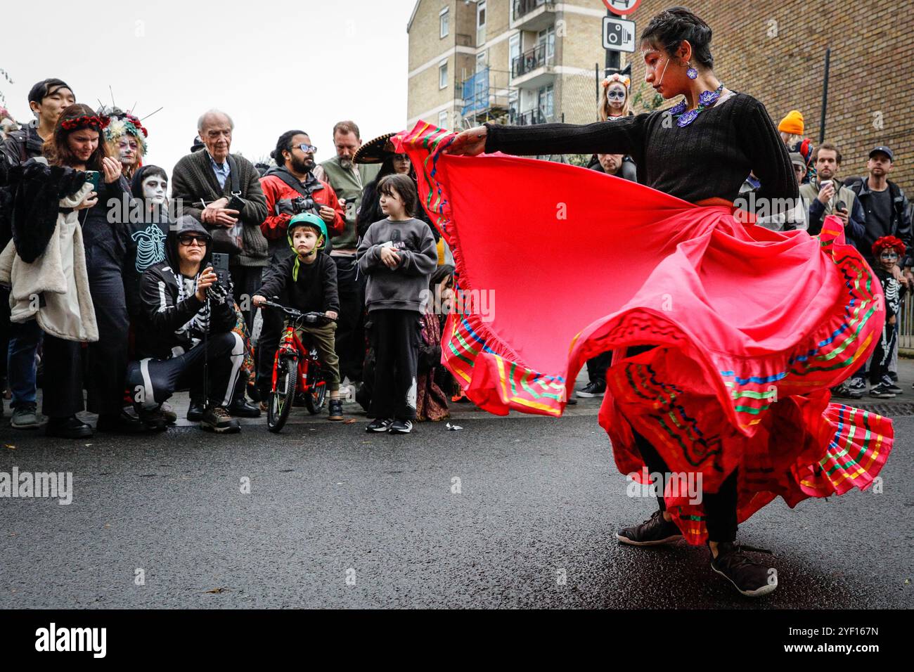London, Großbritannien. November 2024. Eine Tänzerin unterhält die Menge. Die Teilnehmer, viele in lebendigen Gesichtsbemalungen und Kostümen, versammeln sich in der Columbia Road. Der jährliche Tag der Toten und die Parade auf und um die Columbia Road in grüßt den mexikanischen Tag der Toten, ein freudiger Anlass trotz seines Namens, der das Vergehen geliebter Menschen ehrt. Die Teilnehmer kommen in farbenfrohen Kostümen auf. Quelle: Imageplotter/Alamy Live News Stockfoto
