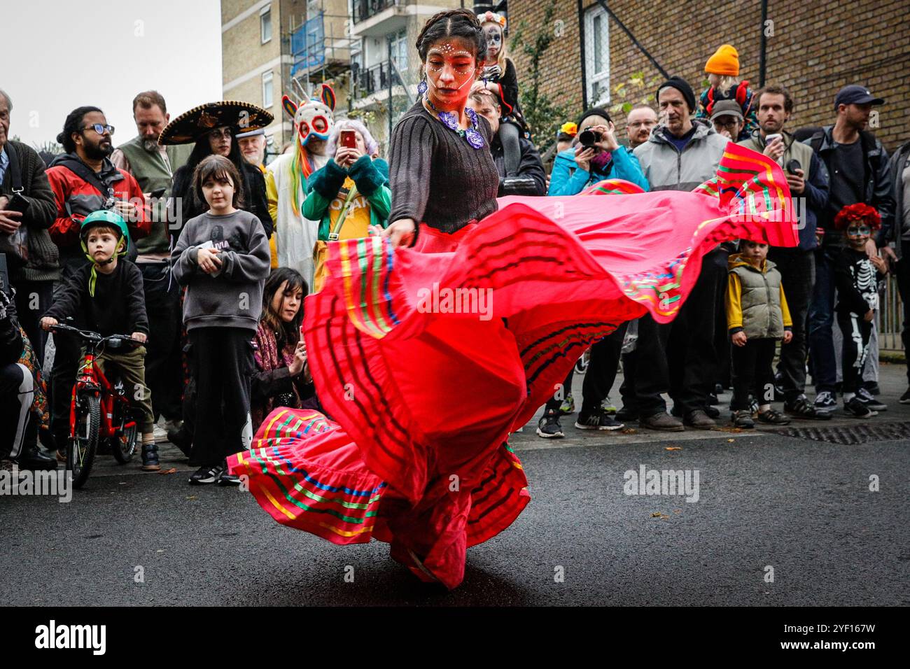 London, Großbritannien. November 2024. Eine Tänzerin unterhält die Menge. Die Teilnehmer, viele in lebendigen Gesichtsbemalungen und Kostümen, versammeln sich in der Columbia Road. Der jährliche Tag der Toten und die Parade auf und um die Columbia Road in grüßt den mexikanischen Tag der Toten, ein freudiger Anlass trotz seines Namens, der das Vergehen geliebter Menschen ehrt. Die Teilnehmer kommen in farbenfrohen Kostümen auf. Quelle: Imageplotter/Alamy Live News Stockfoto