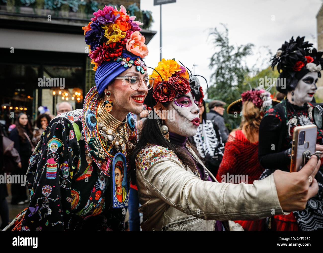 London, Großbritannien. November 2024. Die Teilnehmer, viele in lebendigen Gesichtsbemalungen und Kostümen, versammeln sich in der Columbia Road. Der jährliche Tag der Toten und die Parade auf und um die Columbia Road in grüßt den mexikanischen Tag der Toten, ein freudiger Anlass trotz seines Namens, der das Vergehen geliebter Menschen ehrt. Die Teilnehmer kommen in farbenfrohen Kostümen auf. Quelle: Imageplotter/Alamy Live News Stockfoto