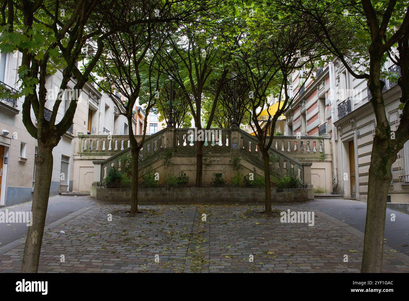 Paris, Frankreich, 10.31.2024 Ein kleiner Wohnplatz mit Bäumen und Treppen zu einer anderen Straße in Montmartre. Stockfoto