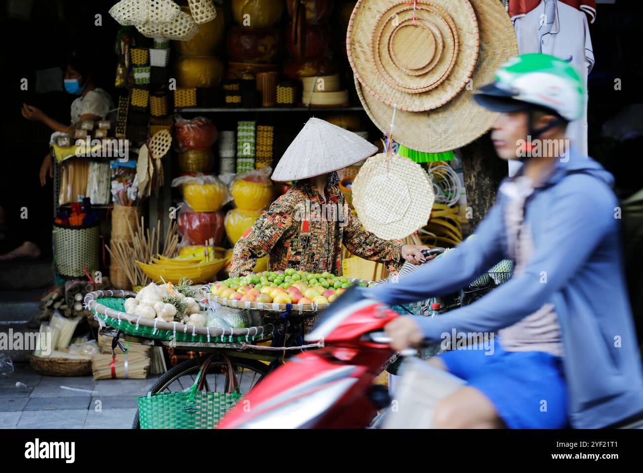 Hanoi, Vietnam - 14. Juli 2023: Vietnamesin, die den traditionellen konischen Hut trägt, der als Non La bekannt ist, verkauft Obst und Gemüse. Stockfoto
