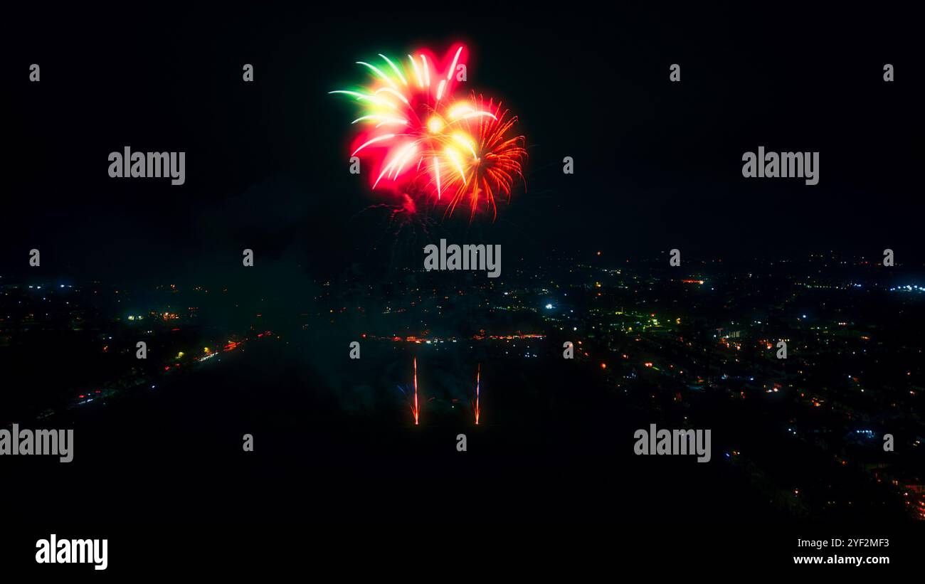 Ein Nachthimmel mit einem großen, roten und grünen Feuerwerk, das in der Mitte explodiert. Das Feuerwerk hat die Form einer Blume mit mehreren Armen. Be Stockfoto