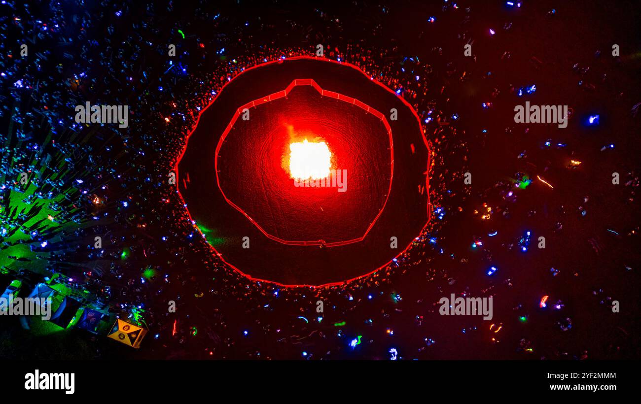 Ein feuriger Ring aus Licht sitzt mitten in einem dunklen, überfüllten Raum. Der Ring ist von einem Ring von Menschen umgeben, und die ganze Szene wird beleuchtet Stockfoto