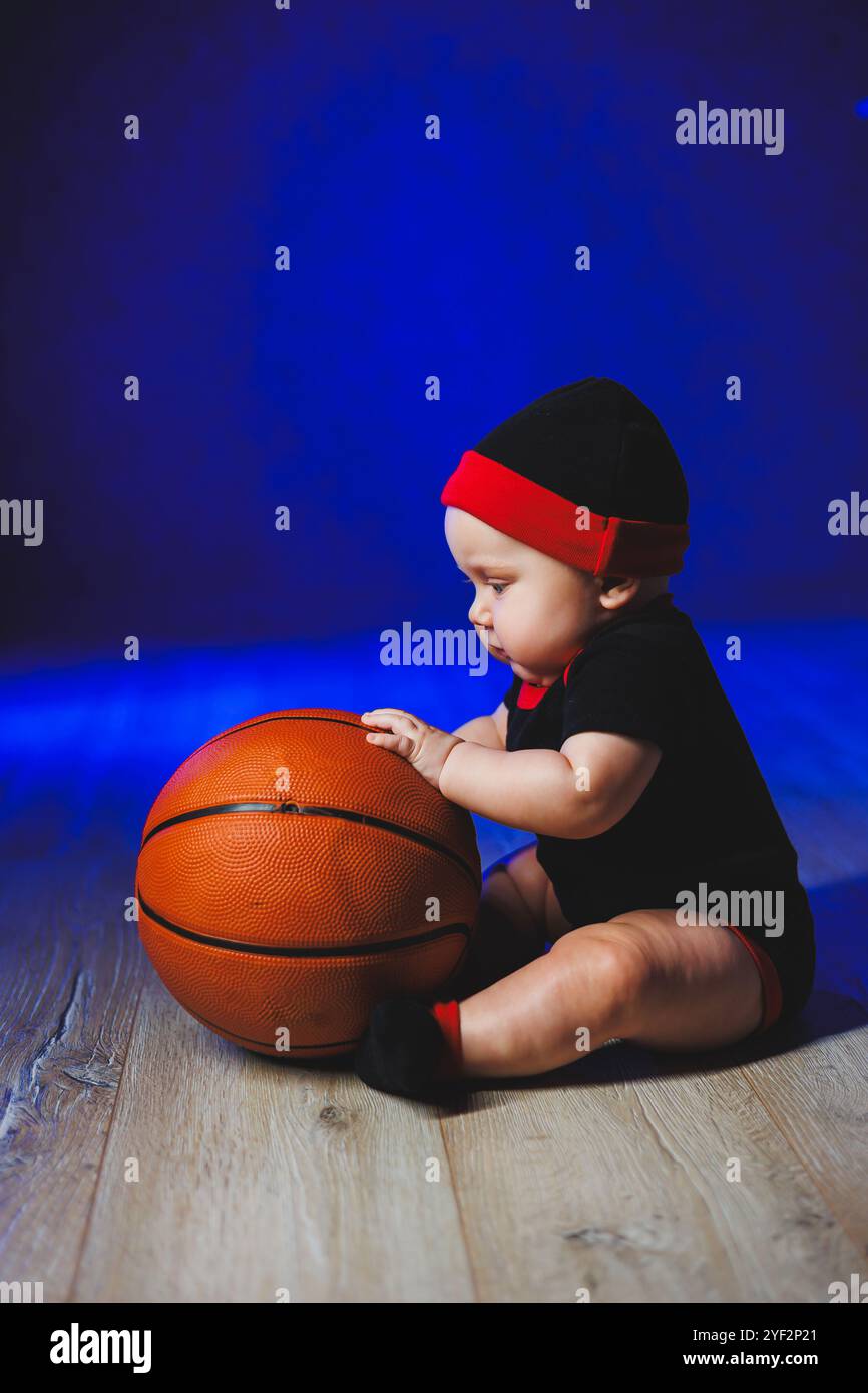 Baby 7 Monate mit Basketball. Sport für Kinder. Baumwollbekleidung für Babys Stockfoto