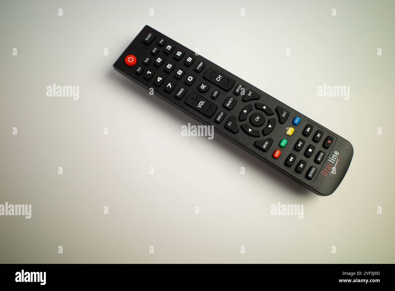 Schwarze TV-Fernbedienung mit bunten Tasten auf einer weißen Oberfläche Stockfoto