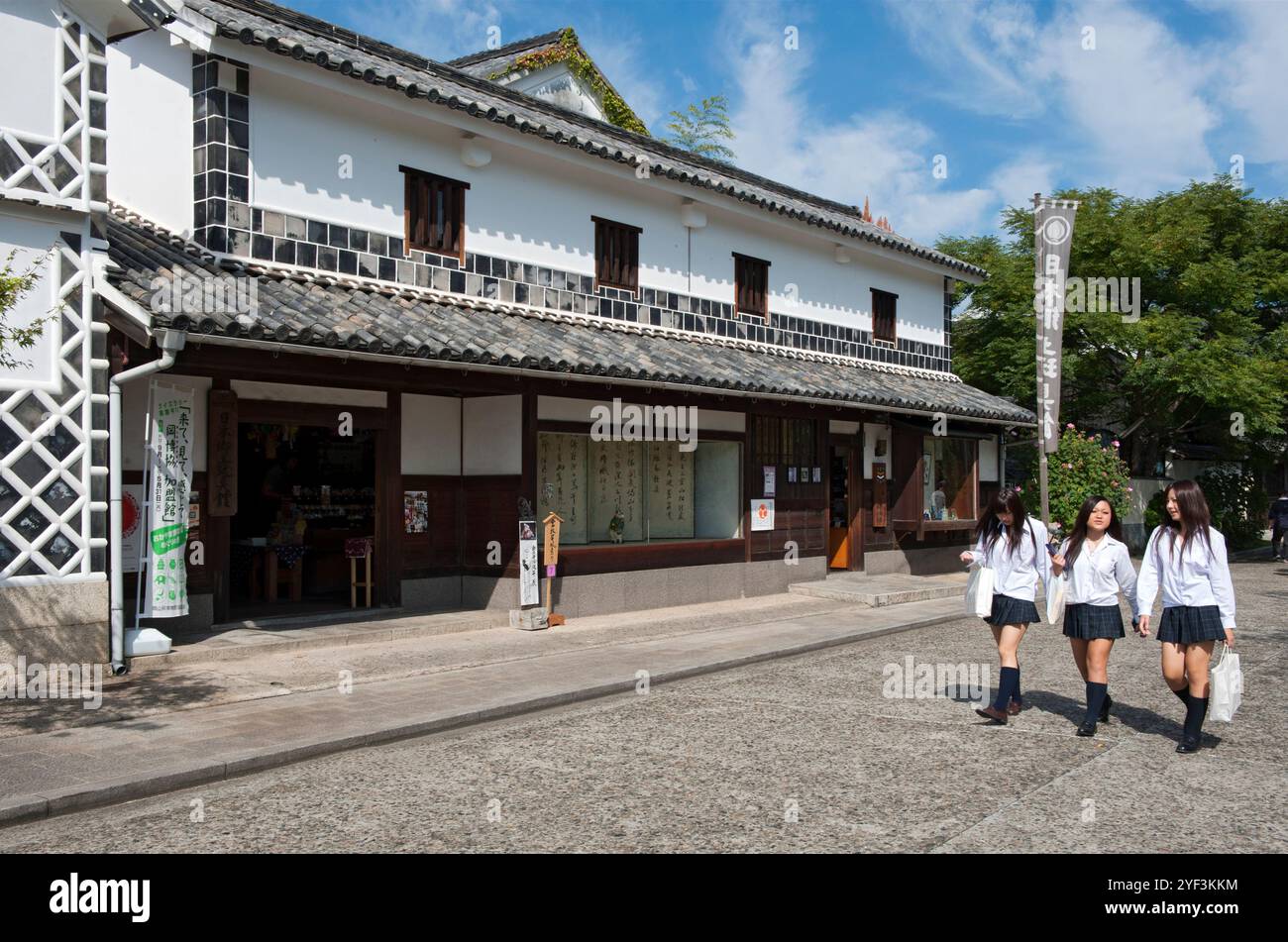 Drei Schulmädchen in passenden Uniformen spazieren die Straße im historischen Viertel Kurashiki Bikan auf einem Sightseeing-Ausflug in Okayama entlang. Stockfoto