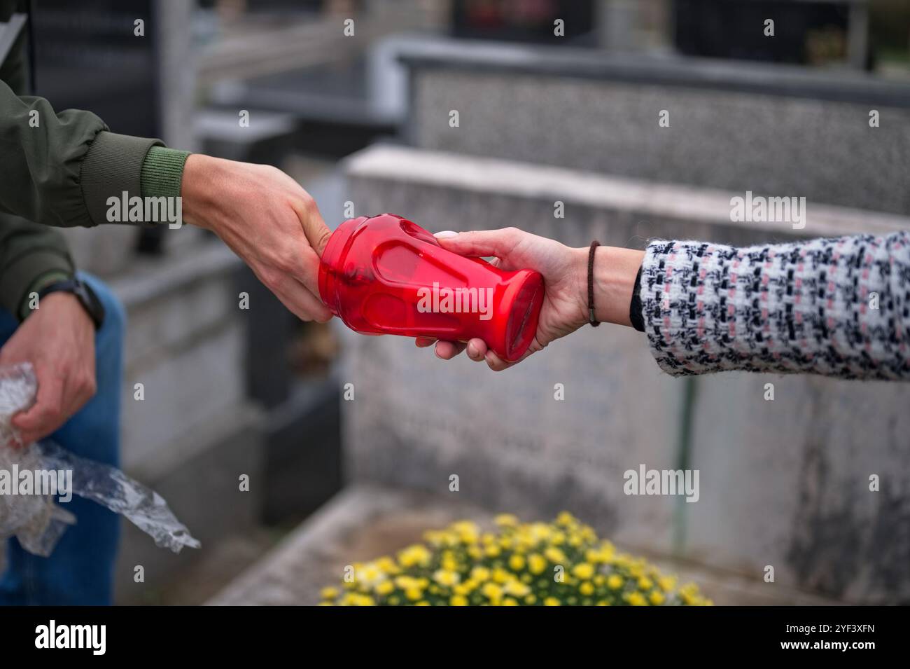 Nahaufnahme von Händen, die eine Kerze auf einem Grab anzünden Stockfoto