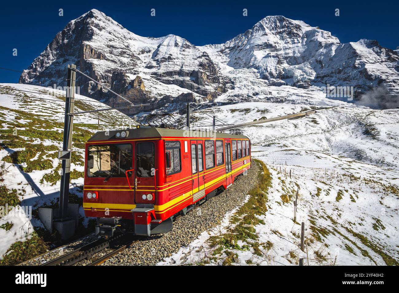 Bergbahn mit modernem Zahnradroter Touristenzug auf der verschneiten Piste. Schweizer berühmte Eisenbahn, Jungfraujoch, kleine Scheidegg, Grindelwald, Bernes Stockfoto