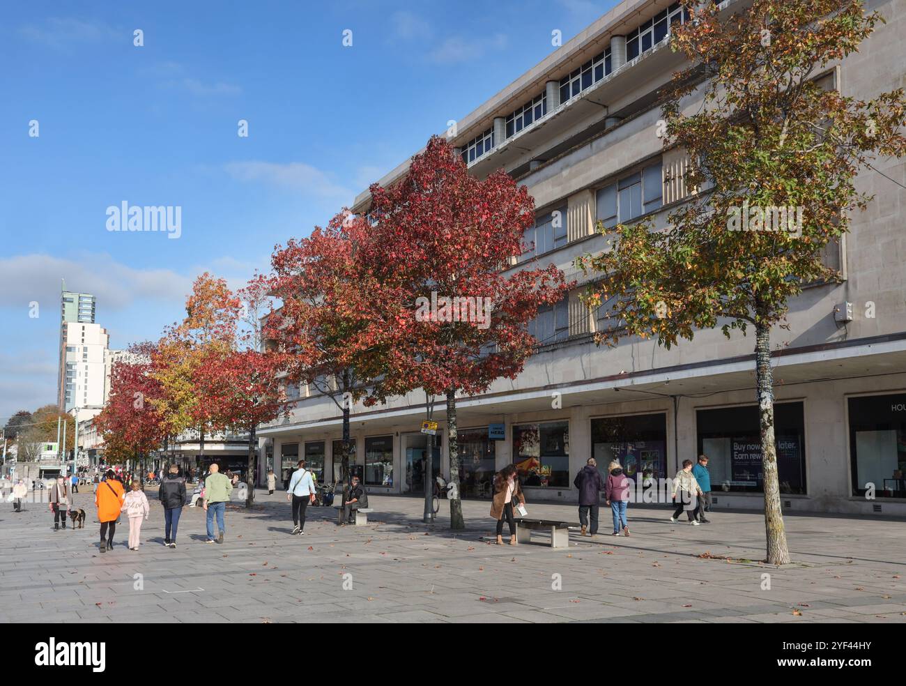 Ein Hauch herbstlicher Farben auf den Bäumen am Armada Way von Plymouth, der durch die Fußgängerzone mit Geschäften und Straßencafés führt. Stockfoto
