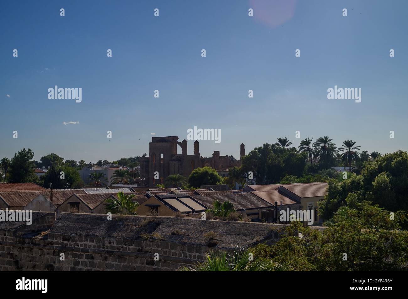 Das Sonnenlicht taucht die Überreste der Geschichte auf und kontrastiert mit dem Grün und den Dächern der nahegelegenen Häuser. Stockfoto