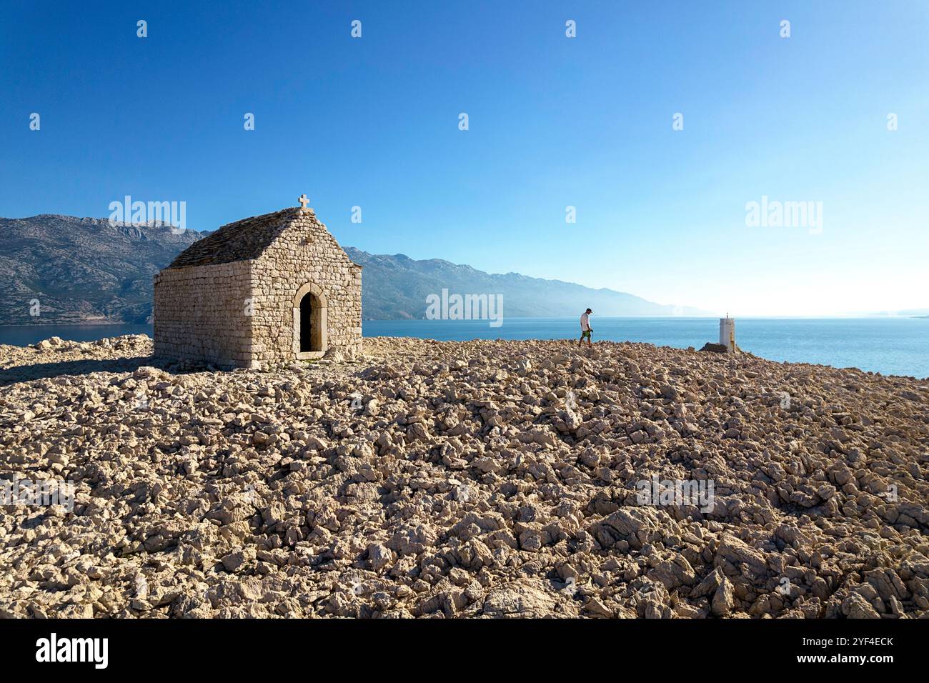 Touristenwanderung zur Kirche St. Christopher auf der Insel pag, einer abgelegenen Kapelle umgeben von Felsen und karger Landschaft und velebit auf der Rückseite, kroatien Stockfoto
